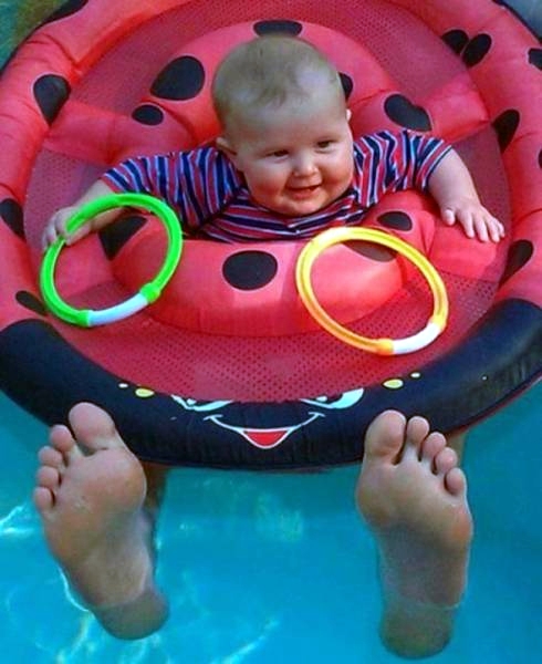 Baby im Pool Schwimmreifen mit riesigen Füßen witzig