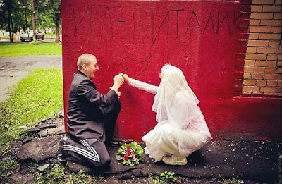 Brautpaar zeichnet Herz mit Pfeil an Wand lustig