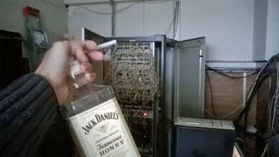 Lustiger IT-Fachmann am Terminal Server Hub säuft Flasche Honig Whisky bei der Arbeit