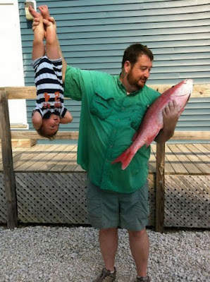 Lustiger Vater hält Baby wie ein Fische hoch