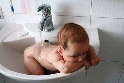 Lustiges Baby fühlt sich wohl im Waschbecken - Abkühlung im Sommer